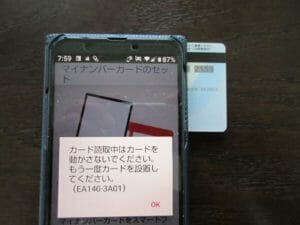 3.マイナンバーカードの番号が書かれた面を写真のようにスマホにピッタリと付ける。